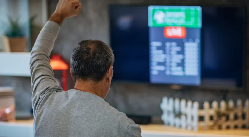 Focused Bangladeshi sports fan monitoring live cricket data across several devices.